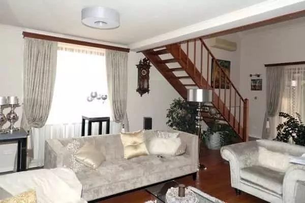 Elegáns nappali ezüstös függönnyel és klasszikus fa karnissal