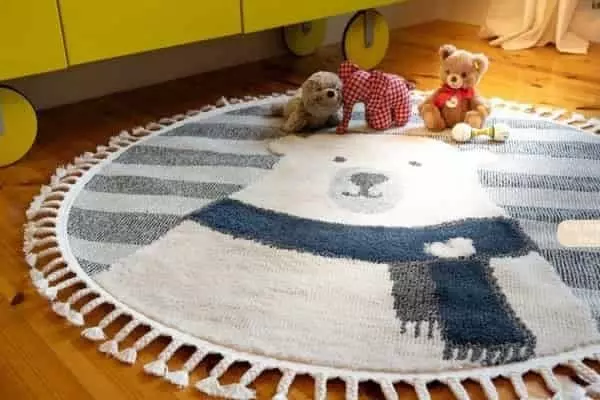 Kerek gyerek szőnyeg bojtokkal, jegesmedve mintával, sárga bútor előtt