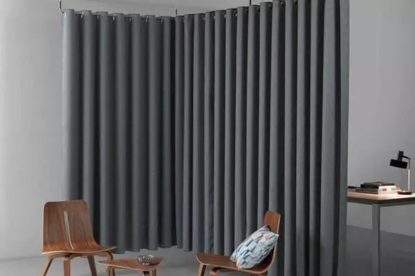 Sötétszürke hangszigetelő függöny modern térben, sarokelválasztásra használva