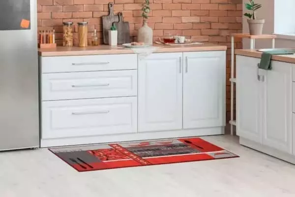 Piros konyhai szőnyeg fehér konyhabútor előtt világos padlón